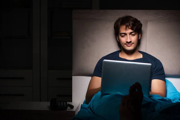 Homem trabalhando no laptop à noite na cama — Fotografia de Stock