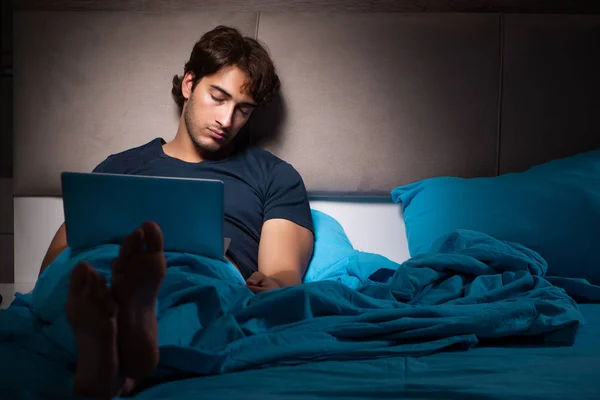 Ο άνθρωπος που εργάζονται για το laptop, το βράδυ στο κρεβάτι — Φωτογραφία Αρχείου