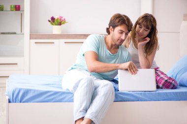 Yatak odasında dizüstü bilgisayar ile genç çift 