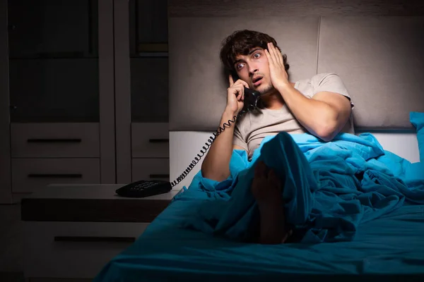 Yatakta telefonda konuşan genç adam — Stok fotoğraf