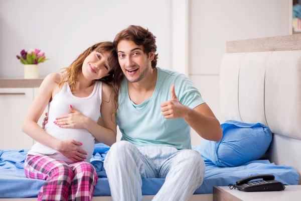 Mujer embarazada con marido en el dormitorio —  Fotos de Stock