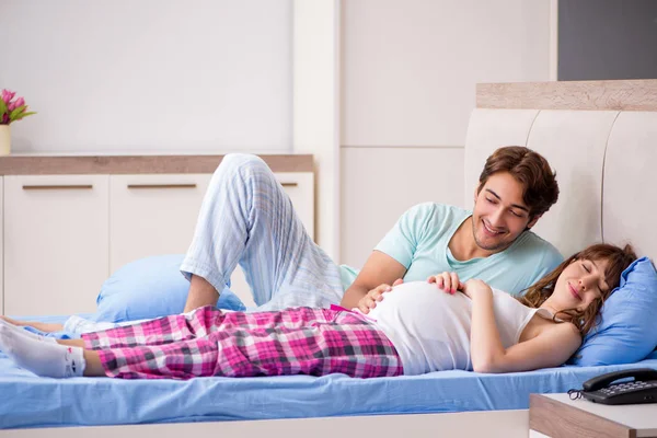 Zwangere vrouw met echtgenoot in de slaapkamer — Stockfoto