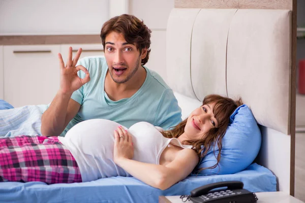 Mujer embarazada con marido en el dormitorio — Foto de Stock