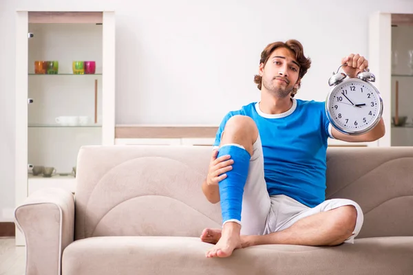 Leg injured young man on the sofa — Stock Photo, Image