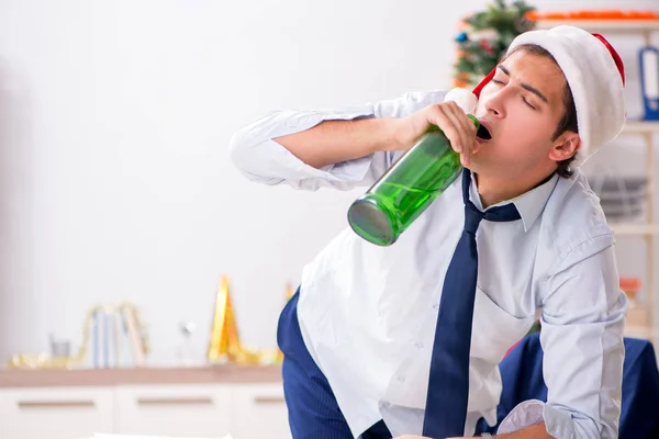 Young handsome employee celebrating Christmas at workplace — Stock Photo, Image