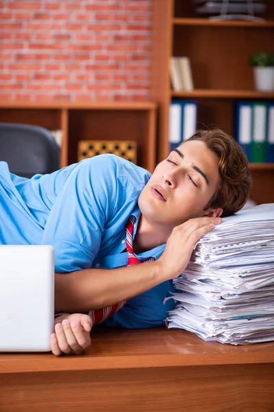 Empleado joven con exceso de trabajo sentado en la oficina —  Fotos de Stock