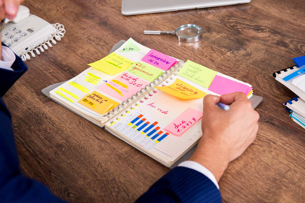 Молодой красивый работник планирует свою рабочую деятельность 