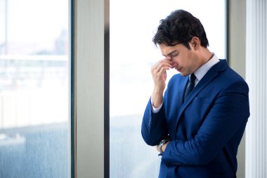 Genç yakışıklı işadamı pencerede duruyor. 