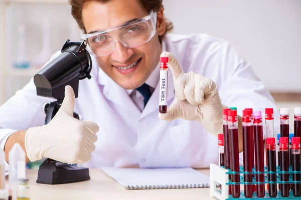 Young handsome lab assistant testing blood samples in hospital — Stock Photo, Image