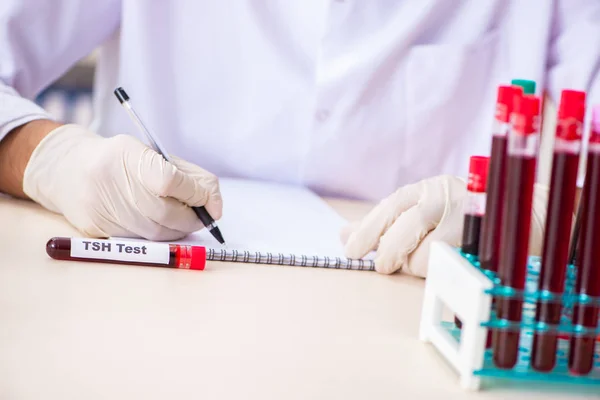 Asisten muda lab tampan yang menguji sampel darah di rumah sakit. — Stok Foto