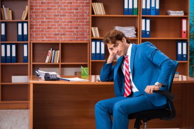 Genç yakışıklı çalışan ofiste oturuyor.  