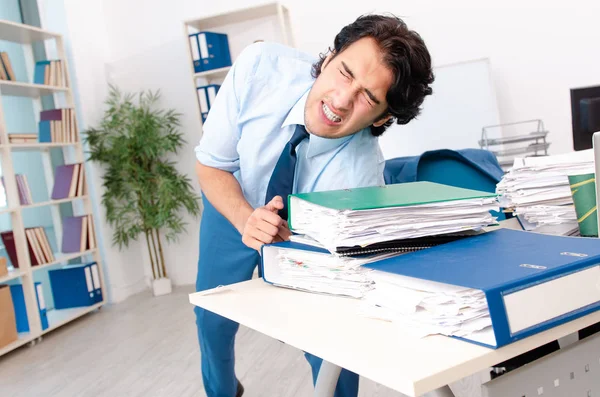 Jonge knappe mannelijke werknemer met te veel werk in het kantoor — Stockfoto