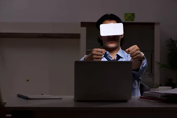 Jeune employé avec des lunettes virtuelles la nuit au bureau — Photo