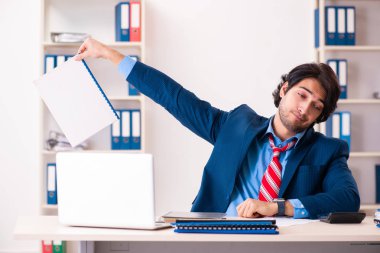 Genç yakışıklı işadamı ofiste oturuyor. 