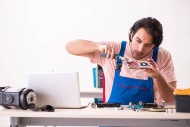 Genç bir erkek müteahhit bilgisayar tamir ediyor.  