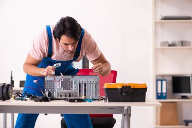 Genç bir erkek müteahhit bilgisayar tamir ediyor.  