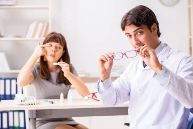 Genç bir kadın, erkek doktor göz doktorunu hastanede ziyaret ediyor.