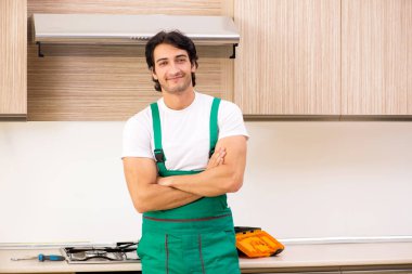 Genç müteahhit mutfakta fırın onarıyor. 