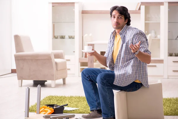 Jovem homem bonito reparando cadeira em casa — Fotografia de Stock