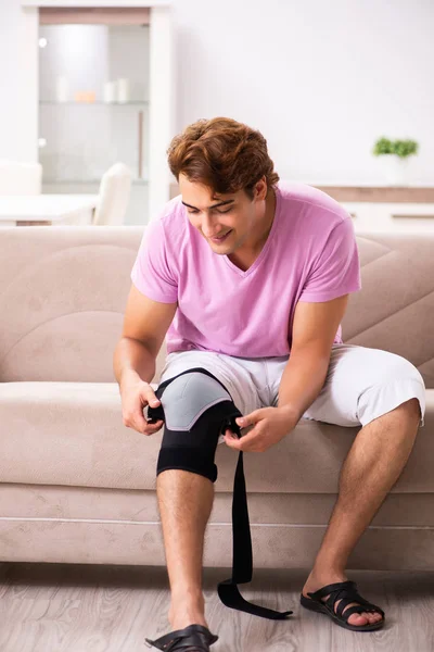 Mladý muž se zraněným kolenem zotavuje doma — Stock fotografie