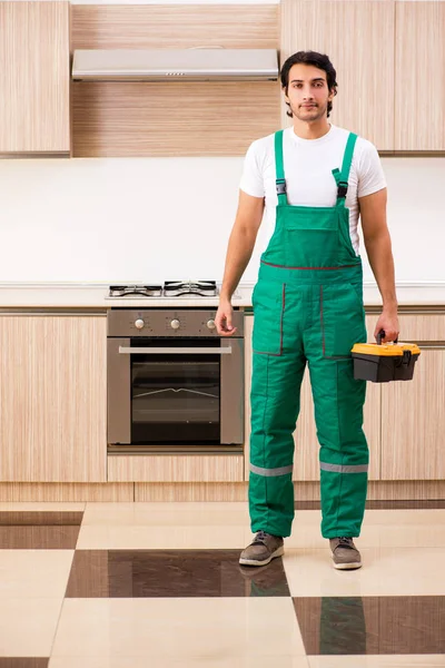Joven contratista reparación de horno en la cocina —  Fotos de Stock