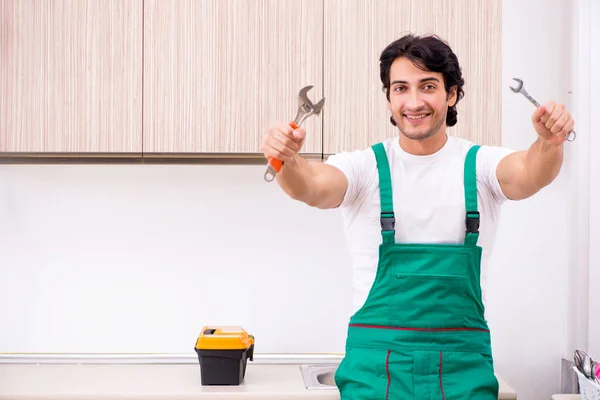 Mladý instalatér opravit kohoutek v kuchyni — Stock fotografie
