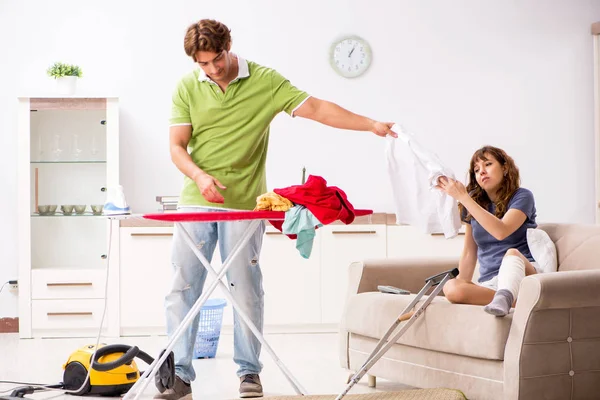 Marido ajudando perna ferida esposa em tarefas domésticas — Fotografia de Stock
