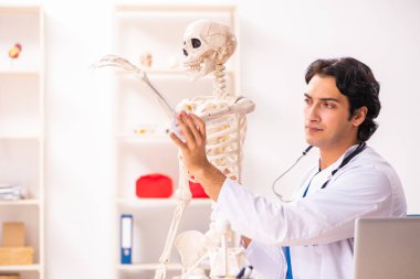İskeleti olan genç erkek doktor. 