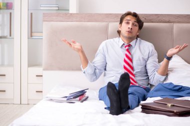 Evde yatakta oturup genç çalışan 