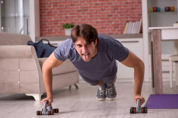 Young handsome man doing sport exercises at home — Stock Photo, Image