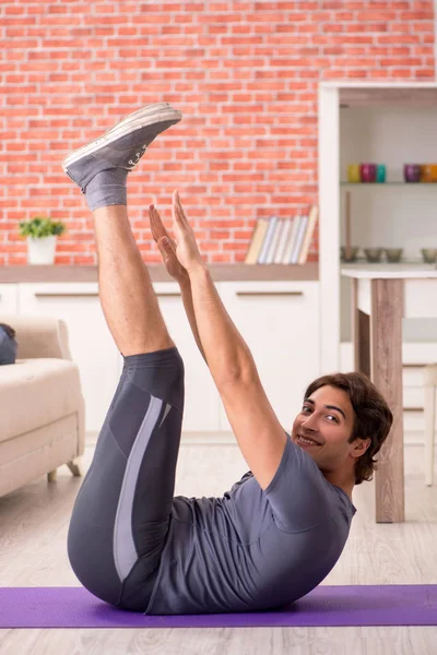 Young handsome man doing sport exercises at home — Stock Photo, Image