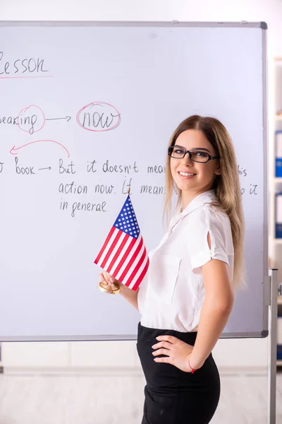 Young female english language teacher standing in front of the b