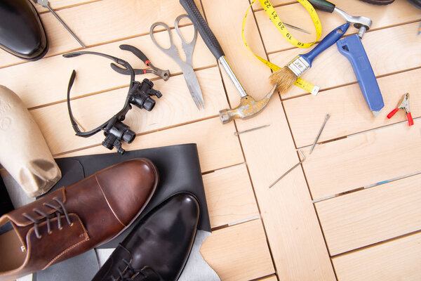 Молодой человек ремонтирует обувь в мастерской
 