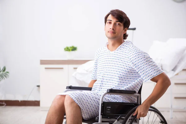 Junger schöner Mann im Rollstuhl im Krankenhaus — Stockfoto