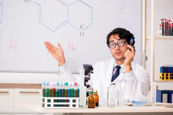 Mladý chemik legrační před bílou tabuli — Stock fotografie