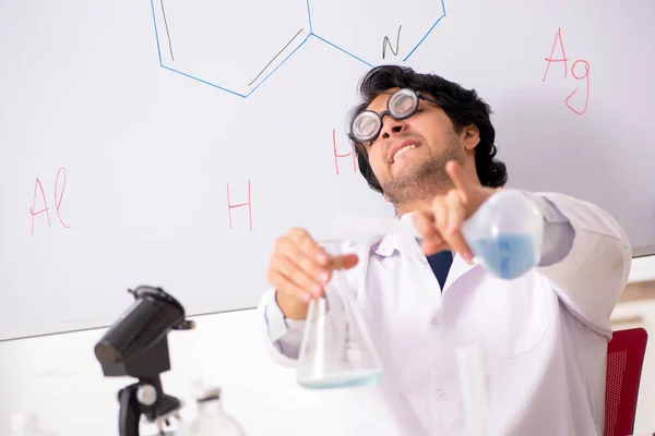 Young funny chemist in front of white board — Stock Photo, Image