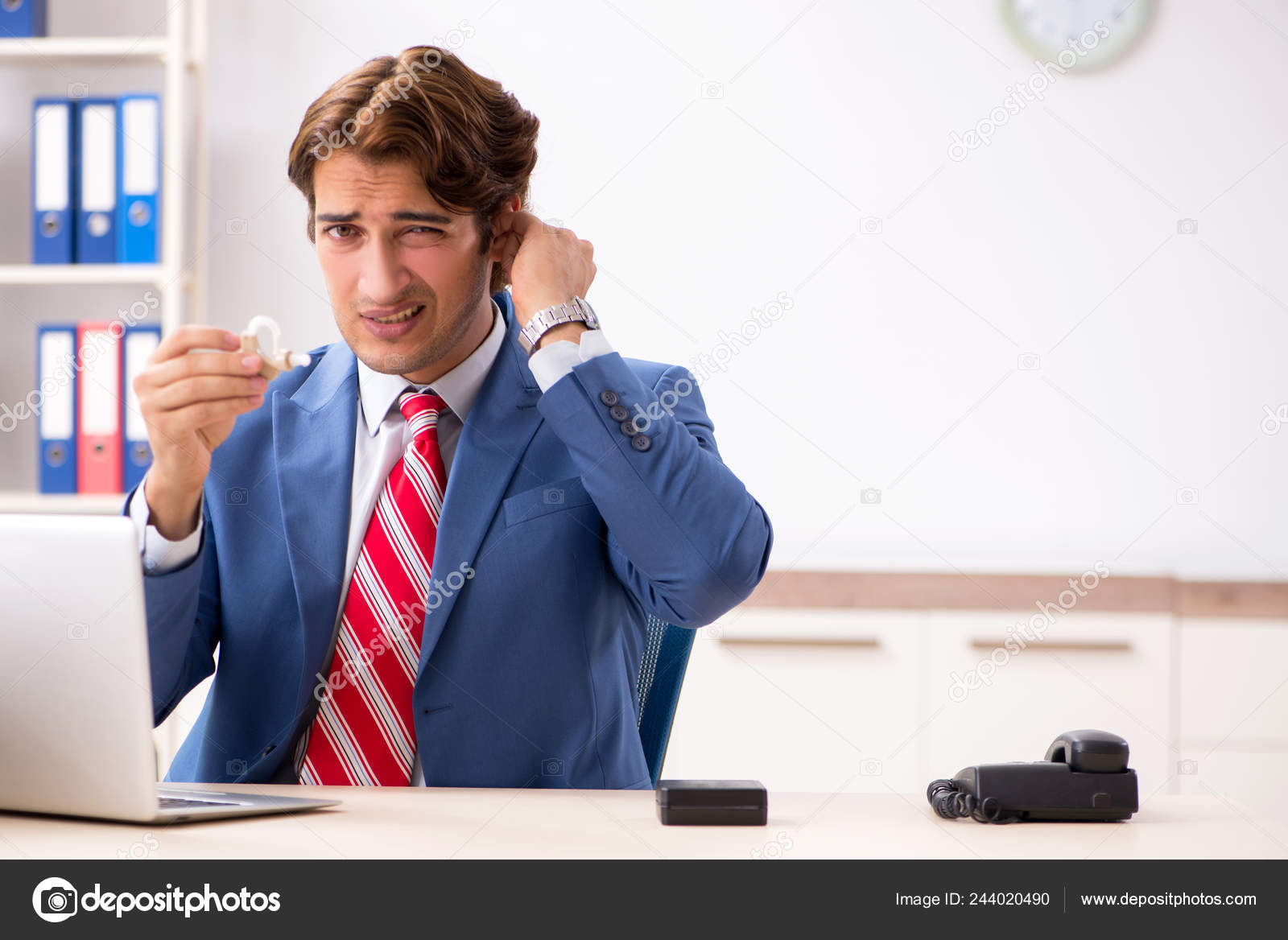 Deaf employee using hearing aid in office Stock Photo by ©Elnur_ 244020490
