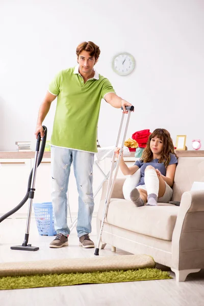 Marido ajudando perna ferida esposa em tarefas domésticas — Fotografia de Stock