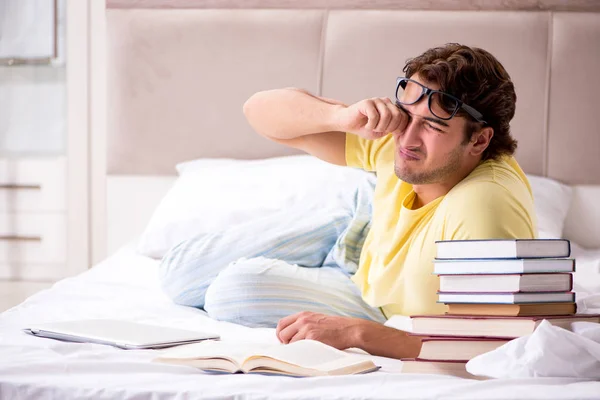 Jovem estudante estudando na cama para exames — Fotografia de Stock