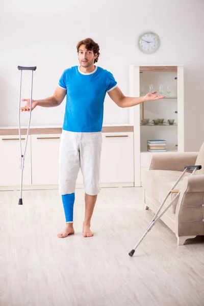 Junger Mann mit Krücken zu Hause am Bein verletzt — Stockfoto