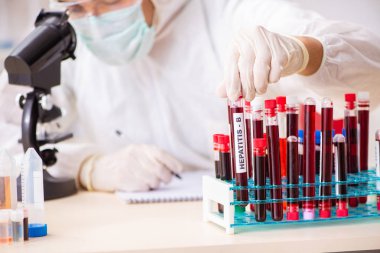 Genç yakışıklı laboratuvar asistanı hastanede kan örnekleri test ediyor.