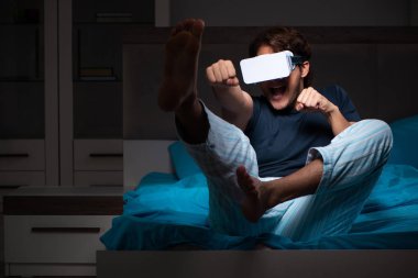 Genç adam, gece yatakta ile bilgisayar oyunu oynamak