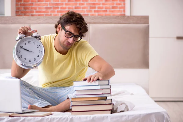 Jovem estudante estudando na cama para exames — Fotografia de Stock