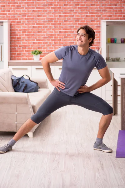 Jovem homem bonito fazendo exercícios esportivos em casa — Fotografia de Stock