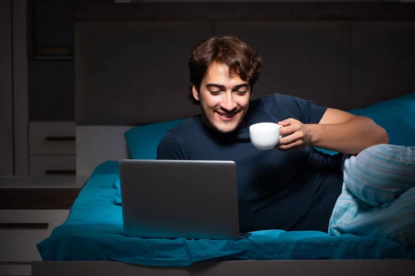 El hombre que trabaja en el ordenador portátil por la noche en la cama —  Fotos de Stock