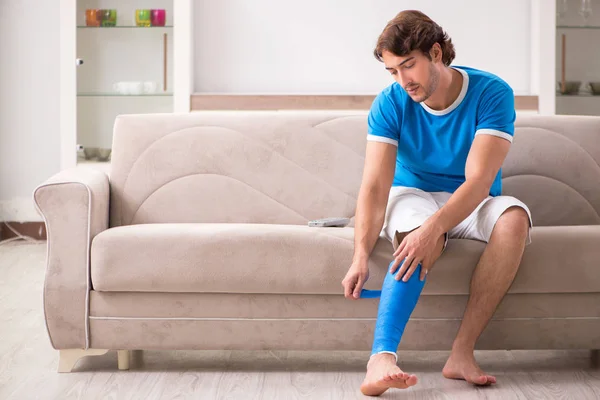 Jambe blessée jeune homme sur le canapé — Photo