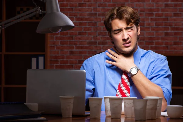 Ung anställd dricker kaffe och jobbar nattskift — Stockfoto