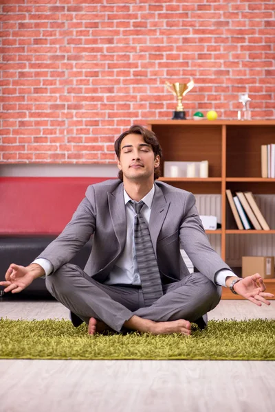 Jovem e bonito funcionário fazendo ioga no escritório — Fotografia de Stock