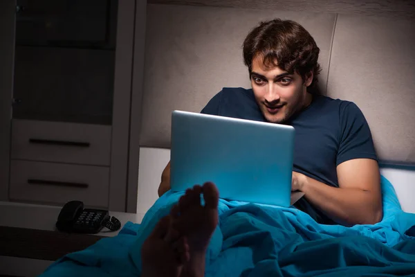 Muž pracuje na notebooku v noci v posteli — Stock fotografie