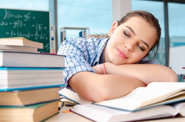 Kız öğrenci sınıfta otururken çok kitap ile